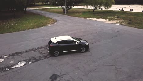 Aerial-view-of-a-black-and-white-Renault-Captur-car-parked-on-raw-asphalt