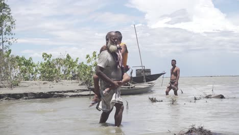 Wide-shot-of-old-man-carrying-a-boy-in-the-water-while-it-is-flooded-all-around