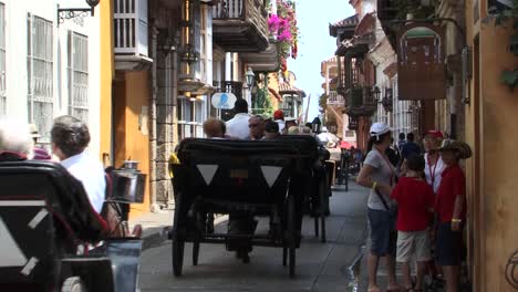 Turistas-Que-Visitan-El-Casco-Antiguo-De-Cartagena,-Colombia-En-Carruajes-Tirados-Por-Caballos.