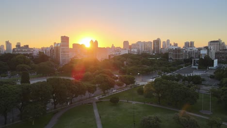 Jib-up-of-Floralis-Generica-steel-sculpture-with-Recoleta-buildings-in-background-at-sunset,-Buenos-Aires