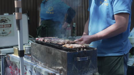 Vendedor-De-Comida-Callejera-Asando-Y-Volteando-Brochetas-De-Carne-Kushiyaki-En-Tokio,-Japón---Tiro-Medio