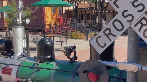 Close-up-of-15-in-gauge-passenger-train-passing-the-Railroad-crossing-at-McCormick-Stillman-Railroad-Park,-Scottsdale,-Arizona