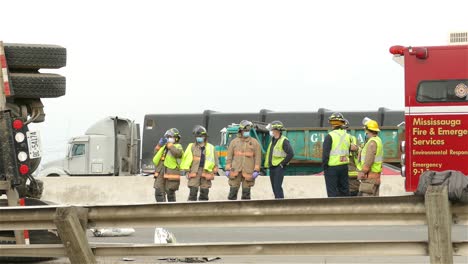 Feuerwehrleute-Entspannen-Sich-Neben-Einem-Umgestürzten-Lastwagen