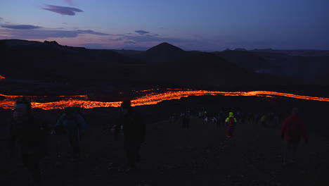 Toma-Panorámica-De-Un-Turista-Que-Visita-Un-Largo-Río-De-Lava-Después-De-La-Erupción-Por-La-Noche