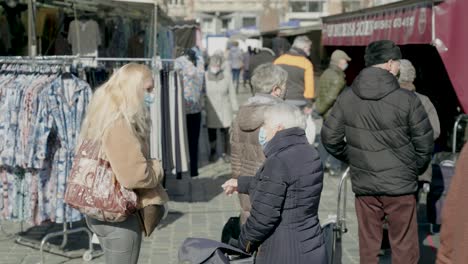 Anciana-Con-Máscara-Médica-Habla-Con-Una-Joven-Enmascarada-En-El-Mercado-Mientras-Esperan-En-La-Fila-Para-El-Carnicero---Tiro-Estático