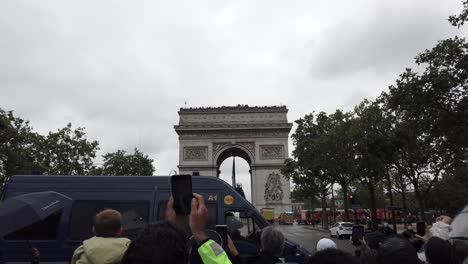 Aufnahme-Von-Menschen,-Die-Während-Des-Nationalfeiertags-Am-14.-Juli-In-Paris,-Frankreich,-Ein-Militärflugzeug-Filmen,-Das-über-Den-Arc-De-Triomphe-Fliegt