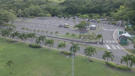 Group-of-tourists-by-yellow-coach-on-Dunn's-River-Falls-parking,-Jamaica,-aerial