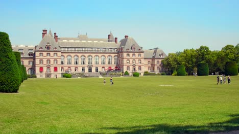 Menschen,-Die-Auf-Dem-Grünen-Rasen-Des-International-University-City-Park-Von-Paris-Mit-Maison-Internationale-Studentenwohnungen-In-Frankreich-Spazieren