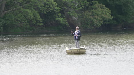 Persona-De-Pie-En-Un-Bote-Pequeño-En-Un-Río-Pacífico-Con-Una-Caña-De-Pescar-En-Tokio,-Japón