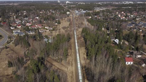 Vista-Aérea-De-Un-Tren-De-Carga-Largo-Que-Viaja-A-Través-De-áreas-Residenciales