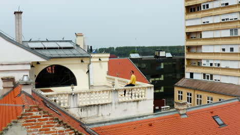 Hombre-Sentado-En-La-Terraza-De-La-Azotea-De-Una-Estructura-Mientras-Bebe-Cerveza-En-La-Ciudad-De-Vukovar,-Croacia