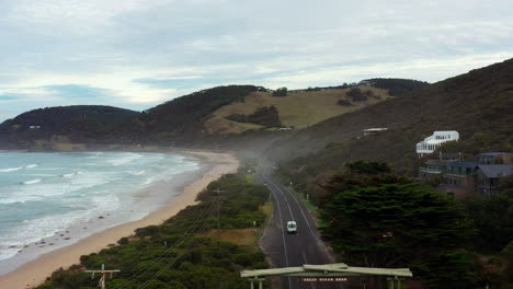 AERIAL-Van-Drives-Through-Great-Ocean-Road-Memorial-Arch-Way,-Australia