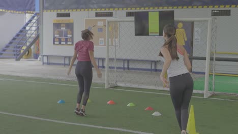 girls-training-on-soccer-field-with-jumping-cones