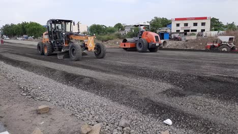 Trabajador-Nivelando-Asfalto-Fresco-En-Un-Sitio-De-Construcción-De-Carreteras