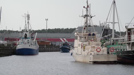 Un-Pequeño-Barco-Nada-A-Través-Del-Canal-Klaipeda-Entre-Otros-Dos-Barcos-En-Un-Día-Soleado