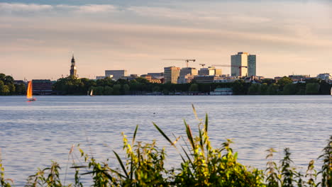 Beautiful-time-lapse-of-Außenalster-with-skyline-and-sailing-boats-passing-by-on-sunny-day-in-Hamburg,-Germany