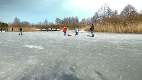 Children-play-on-a-frozen-pond-in-a-city-park-during-freezing-temperatures-in-February,-which-lasted-only-one-week-in-the-Netherlands-in-2021