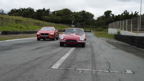 Coche-Rojo-Antiguo-En-La-Carretera-Jaguar-I-pace-Junto-Con-El-Nuevo-Jaguar-I-pace-Eléctrico