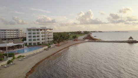 AERIAL---Hotel,-swimming-pool-and-a-small-bay-in-Cancun,-Mexico,-forward-shot