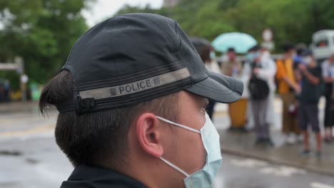 Ein-Polizist-Steht-Im-Regen-Wache,-Während-Er-In-Hongkong-Eine-Gesichtsmaske-Trägt