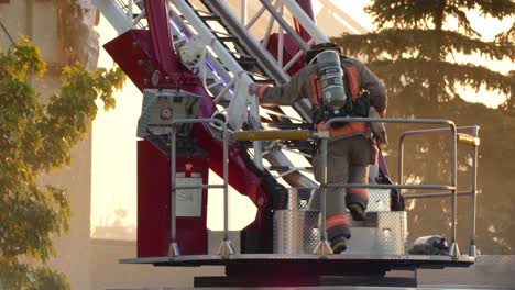 Bombero-Con-Casco-De-Seguridad-Y-Uniforme-Con-Extintor-En-La-Espalda-Sube-A-La-Escalera-De-Un-Camión-De-Bomberos