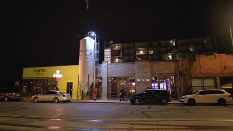 Escaparate-De-Cafetería-Y-Cervecería-A-Lo-Largo-De-La-Carretera-En-El-Centro-De-Tucson-Con-Autos-Estacionados-En-La-Noche