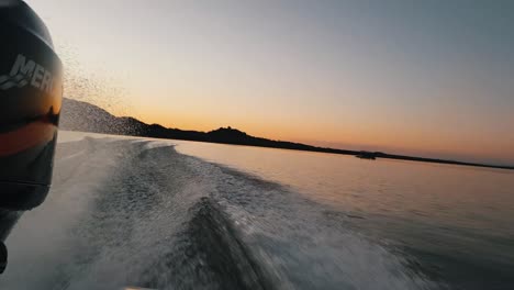 Vista-Desde-Detrás-De-Un-Barco-De-Lubina-Acelerando-Con-Una-Impresionante-Puesta-De-Sol-En-La-Distancia