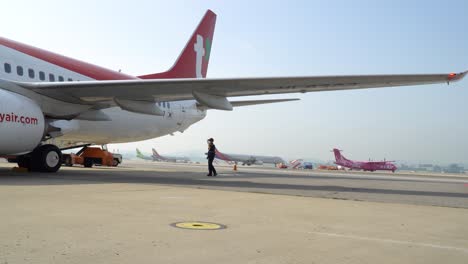 Airport-Worker-In-Uniform-Walking-Under-The-Wing-Of-T'way-Air-Boeing-Parked-At-The-Ramp-Of-Gimpo-Domestic-Airport-In-Seoul,-South-Korea