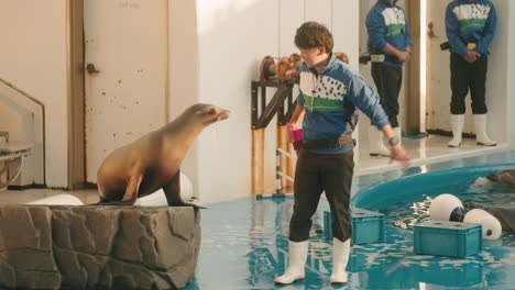 Actuación-De-Una-Foca-Entrenada-En-El-Acuario-Sendai-Umino-mori,-El-Entrenador-Masculino-Interactúa-Con-La-Foca---Plano-General