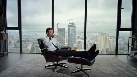 Businessman-sitting-on-chair-in-office-interior.-Business-man-drinking-scotch