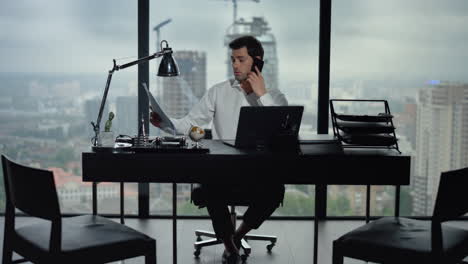 Hombre-De-Negocios-Hablando-Por-Teléfono-Inteligente-En-La-Oficina.-Empresario-Mirando-Documentos
