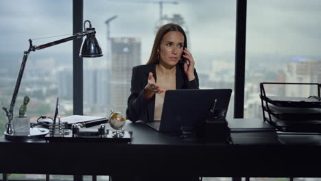 Businesswoman-talking-on-smartphone-in-office.-Woman-looking-at-screen-of-laptop