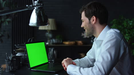Positive-businessman-video-chatting-online-on-laptop-with-green-screen-in-office