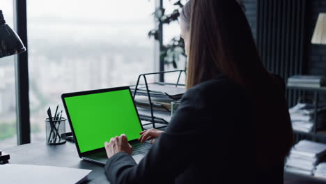 Confident-businesswoman-having-video-call-at-laptop-with-green-screen-in-office