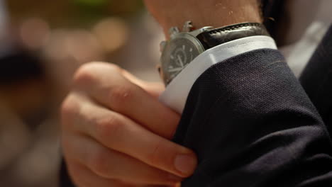 Rich-man-buttoning-up-shirt-sleeve-under-arch.-Man-hands-with-wrist-watch