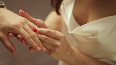 Bride-hand-putting-ring-on-groom-finger-on-wedding.-Woman-holding-man-hand