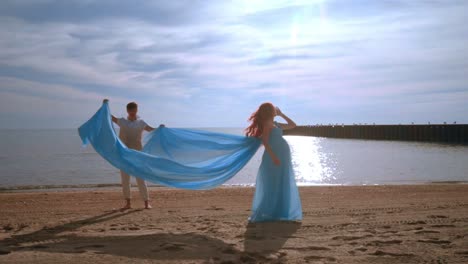 Woman-pregnant-on-beach-sea.-Pregnant-woman-in-blue-dress-flying-on-wind
