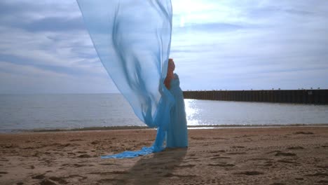 Pregnant-woman-with-blue-cloth-flying-on-beach.-Pregnancy-concept