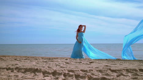 Pregnant-woman-in-blue-dress-posing-on-beach.-Beach-holiday.-Romantic-woman