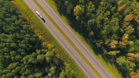 Highway-road-between-trees.-Aerial-view-of-truck-driving-at-road-at-forest