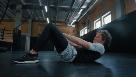 Young-kickboxer-doing-crunches-in-sport-club.-Sportsman-working-on-abc-at-gym