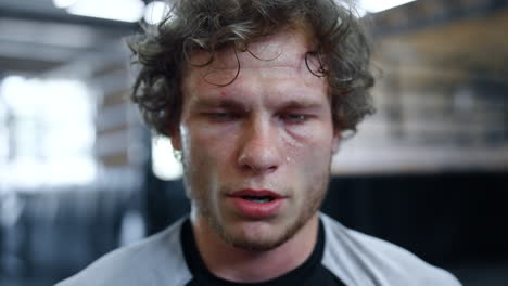 Tired-fighter-having-break-in-fitness-center.-Handsome-kickboxer-sweating-at-gym