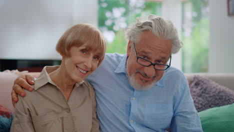Smiling-senior-man-and-woman-looking-at-camera.-Husband-hugging-wife