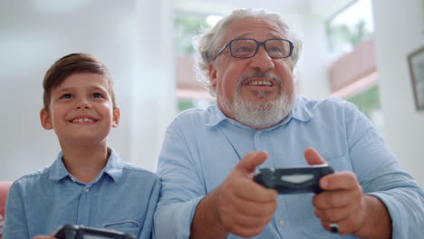 Portrait-of-cheerful-grandson-and-grandfather-playing-video-game-in-living-room