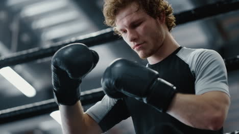 Focused-fighter-waiting-for-fight-in-sport-club.-Kickboxer-wearing-boxing-gloves