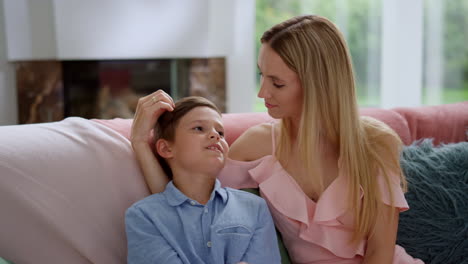 Mother-and-son-talking-together-in-living-room.-Careful-woman-touching-boy-hair