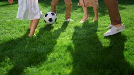 Closeup-of-parents-and-kids-feet-playing-with-soccer-ball-in-green-park