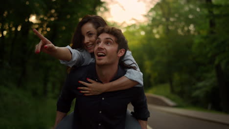 Pretty-woman-piggyback-man-and-happy-people-having-fun-at-summer-weekend-outdoor