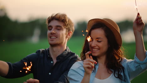 Happy-couple-dancing-with-sparklers-at-summer-park.-Excited-people-enjoy-party