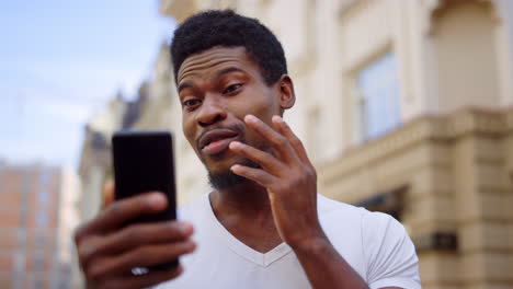 Excited-afro-guy-having-video-call-on-street.-Man-making-hand-gesture-outdoors